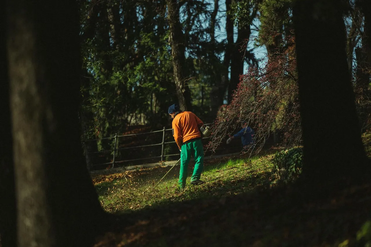 A groundskeeper mowing the grass at a campsite on a turnaround day